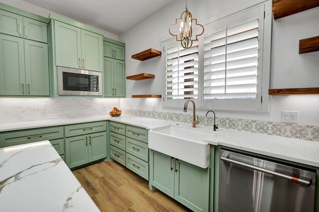 kitchen with light stone countertops, decorative light fixtures, stainless steel appliances, and green cabinets