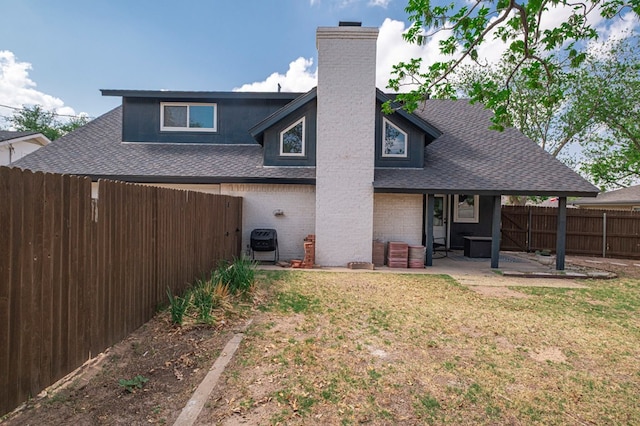 back of property with a chimney, a patio, a fenced backyard, and a shingled roof
