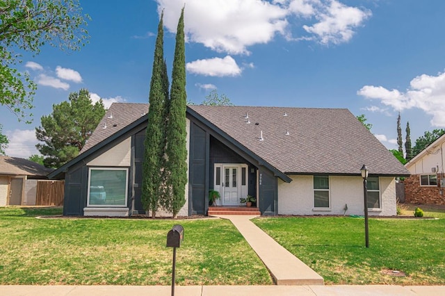 mid-century inspired home with brick siding, a front yard, and roof with shingles