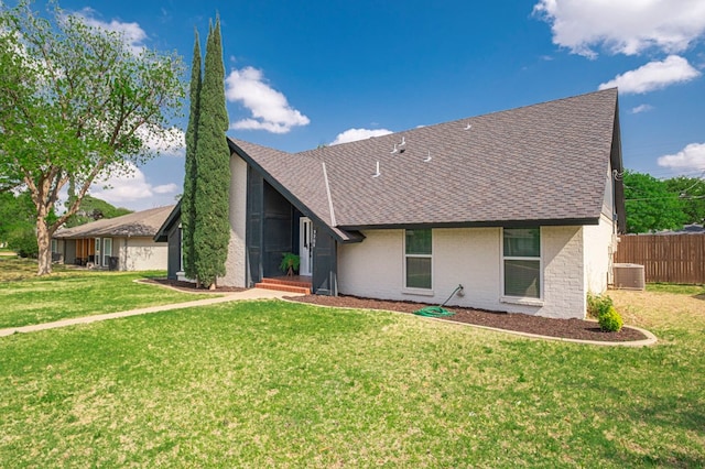 view of front of property with fence, a front lawn, a shingled roof, and central AC unit