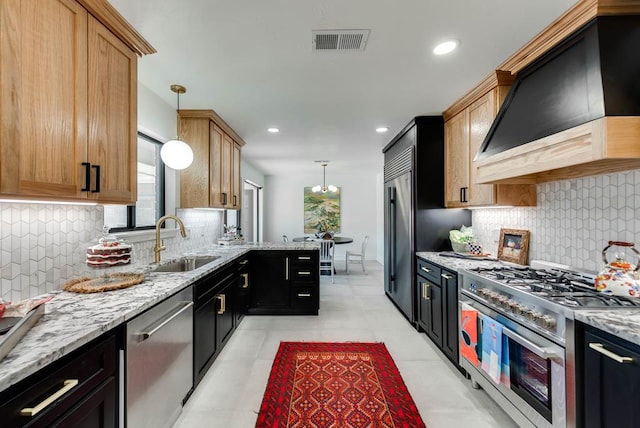 909 Pine Ct, Midland, TX 79705 - kitchen with stainless steel appliances, custom exhaust hood, decorative light fixtures, light stone countertops, and recessed lighting