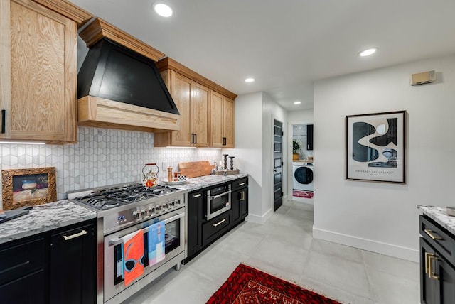 909 Pine Ct, Midland, TX 79705 - kitchen featuring custom exhaust hood, range with two ovens, washer / clothes dryer, decorative backsplash, and light stone counters