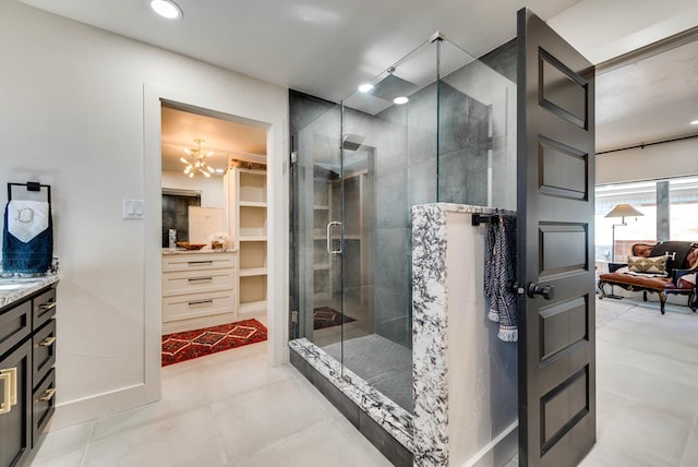 909 Pine Ct, Midland, TX 79705 - bathroom featuring vanity, a stall shower, a spacious closet, a chandelier, and recessed lighting