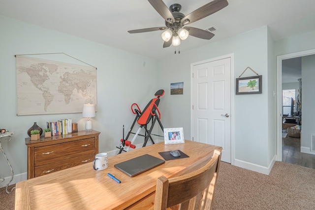 carpeted office space featuring ceiling fan