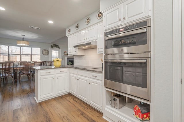 kitchen featuring stainless steel double oven, kitchen peninsula, hanging light fixtures, and white cabinets