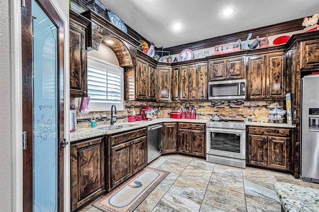1210 S County Rd 1117, Midland, TX 79706 - kitchen featuring appliances with stainless steel finishes, a sink, tasteful backsplash, dark brown cabinets, and stone tile floors
