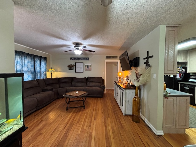 1806 38th St, Snyder, TX 79549 - living room featuring light wood-style flooring, a ceiling fan, a textured ceiling, and baseboards
