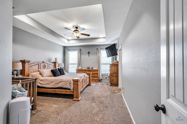 1321 Pine Ave, Midland, TX 79705 - bedroom featuring light carpet, a raised ceiling, a textured wall, and a ceiling fan