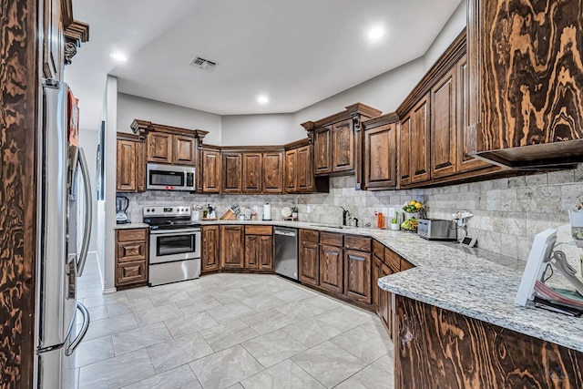1321 Pine Ave, Midland, TX 79705 - kitchen with stainless steel appliances, backsplash, light stone counters, and dark brown cabinetry