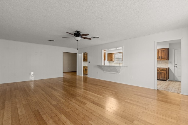2826 Beechwood St, Odessa, TX 79761 - unfurnished living room featuring a ceiling fan, light wood-style flooring, and a textured ceiling