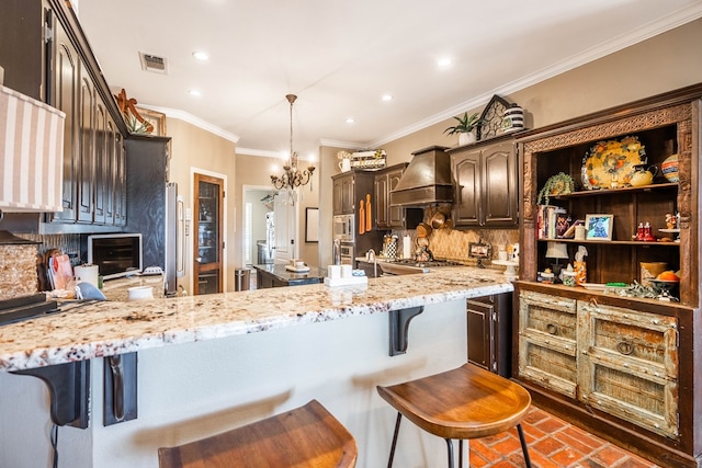 kitchen with light stone countertops, premium range hood, kitchen peninsula, a breakfast bar area, and dark brown cabinets