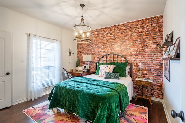 bedroom featuring a chandelier, dark wood-type flooring, and brick wall