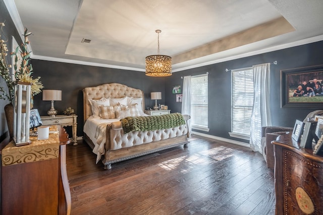 bedroom with dark hardwood / wood-style floors, ornamental molding, and a tray ceiling