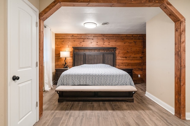 bedroom with hardwood / wood-style floors and wooden walls