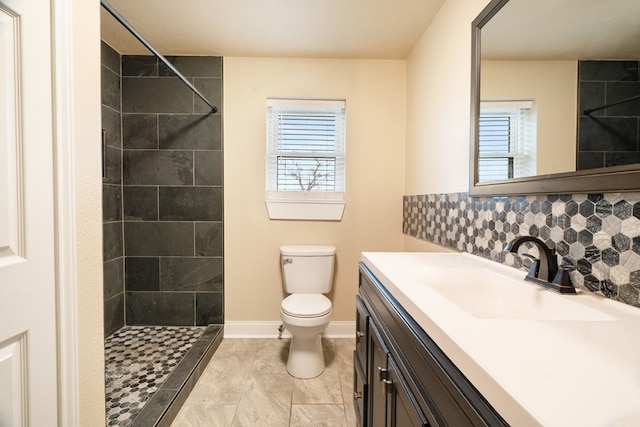 bathroom with vanity, toilet, tiled shower, and tasteful backsplash