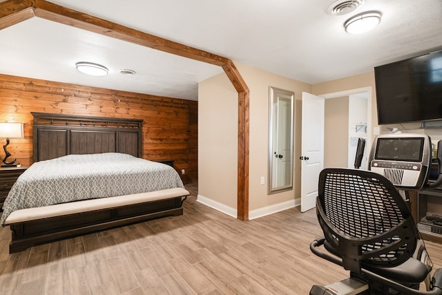 bedroom featuring light hardwood / wood-style flooring and wooden walls