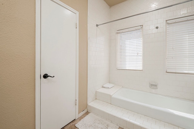 full bath featuring a tub to relax in and a textured wall