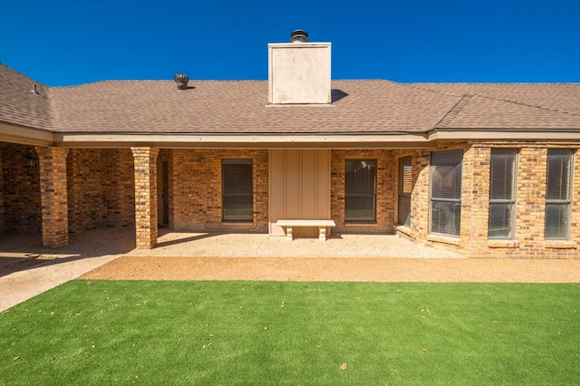 back of property with a shingled roof, a lawn, a chimney, and board and batten siding