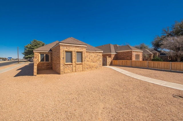 ranch-style home featuring brick siding and fence