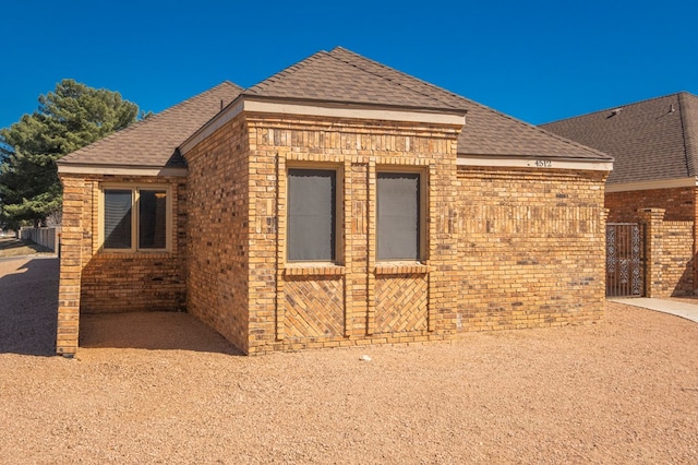 view of side of property featuring brick siding and roof with shingles