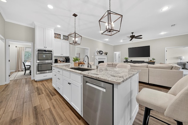 6113 Turtle Creek Rd, Midland, TX 79707 - kitchen featuring stainless steel appliances, ceiling fan, a center island with sink, ornamental molding, and light wood-style flooring