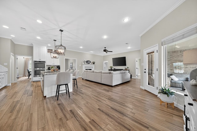 6113 Turtle Creek Rd, Midland, TX 79707 - living area featuring crown molding, a ceiling fan, light wood-style floors, recessed lighting, and a fireplace