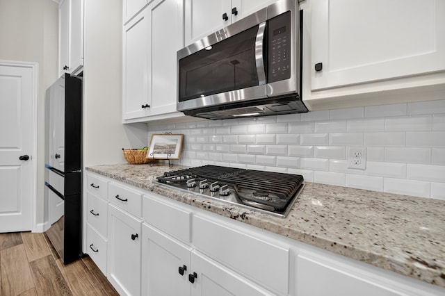 6113 Turtle Creek Rd, Midland, TX 79707 - kitchen with appliances with stainless steel finishes, white cabinetry, decorative backsplash, and light stone counters