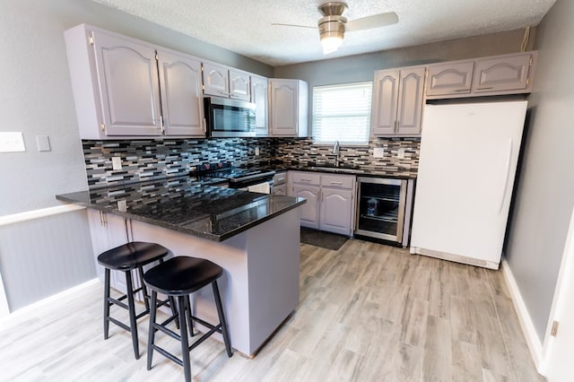 10905 E County Rd 107, Midland, TX 79706 - kitchen featuring stainless steel appliances, wine cooler, a peninsula, tasteful backsplash, and a sink