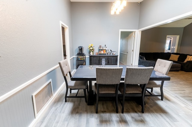 10905 E County Rd 107, Midland, TX 79706 - dining room featuring light wood-type flooring, a high ceiling, a chandelier, and a wainscoted wall