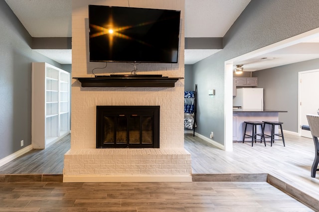 10905 E County Rd 107, Midland, TX 79706 - detailed view of freestanding refrigerator, baseboards, a fireplace, and wood finished floors