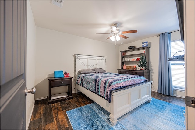 bedroom with a ceiling fan, wood finished floors, visible vents, and baseboards