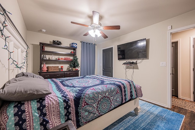 bedroom with ceiling fan, dark wood-type flooring, and baseboards