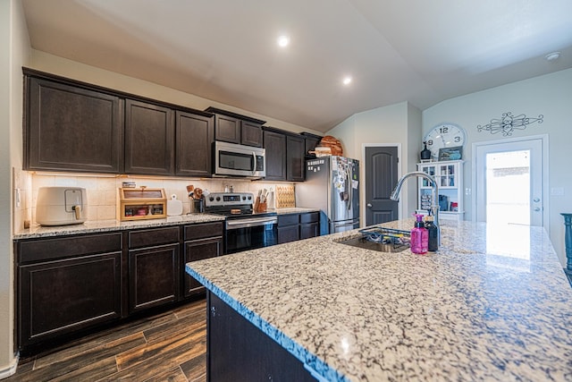 kitchen featuring backsplash, appliances with stainless steel finishes, lofted ceiling, and a sink