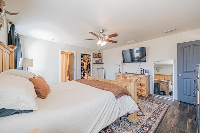 bedroom featuring a spacious closet, visible vents, dark wood-type flooring, ceiling fan, and a closet