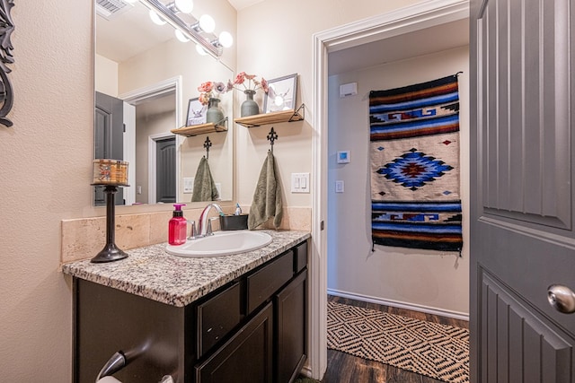 bathroom with vanity, wood finished floors, visible vents, and baseboards