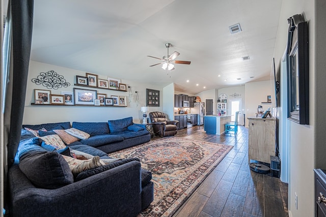 living room with a ceiling fan, lofted ceiling, visible vents, and dark wood-style flooring