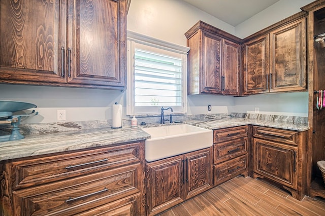 kitchen with light stone counters, sink, and dark brown cabinets