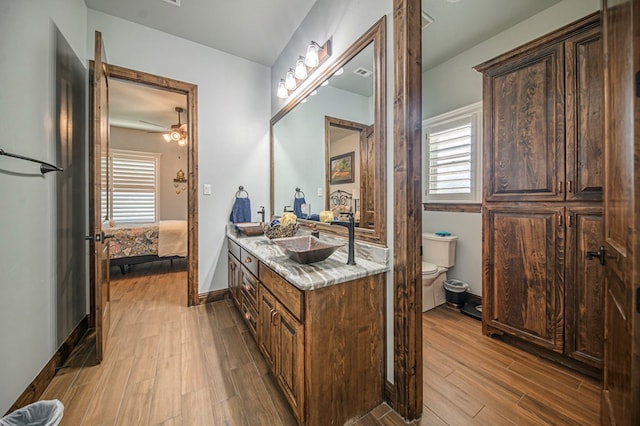 bathroom with ceiling fan, vanity, wood-type flooring, and toilet