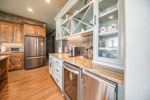 kitchen featuring white cabinetry, light stone countertops, tasteful backsplash, wine cooler, and stainless steel fridge