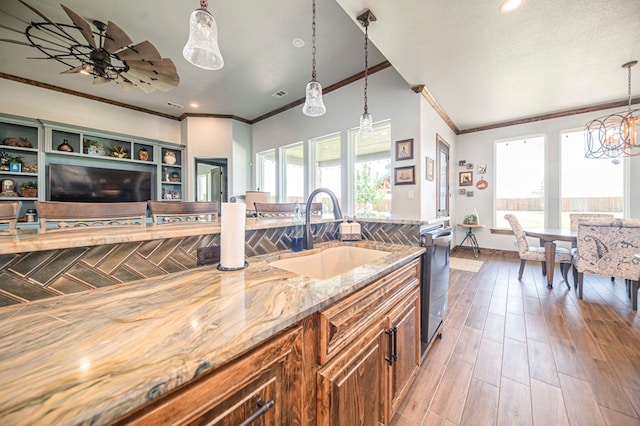 kitchen with light stone countertops, sink, hardwood / wood-style floors, decorative light fixtures, and ceiling fan with notable chandelier