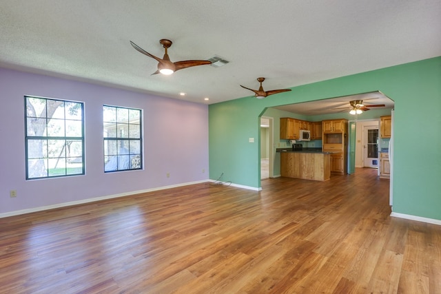 2100 Edgemere Rd, Big Spring, TX 79720 - unfurnished living room with a ceiling fan, visible vents, arched walkways, wood finished floors, and baseboards