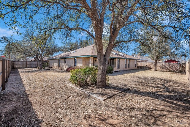 back of property with a fenced backyard and brick siding