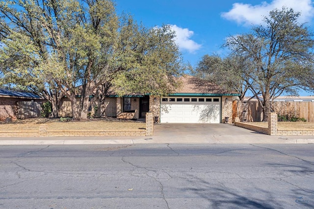 view of front of home with brick siding, concrete driveway, a garage, and fence