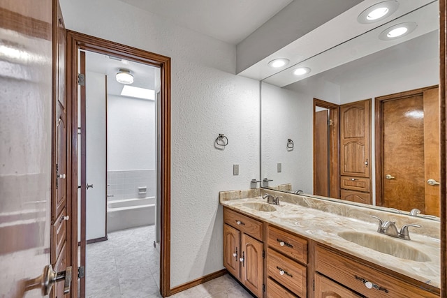 bathroom with a sink, baseboards, and double vanity