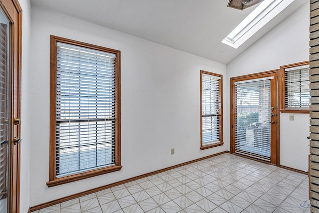 foyer entrance with vaulted ceiling with skylight, light floors, and baseboards