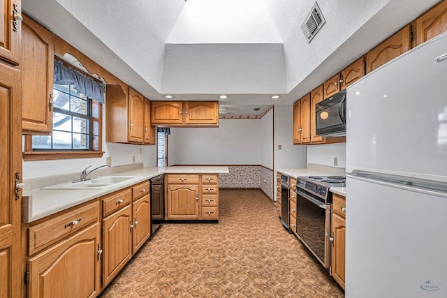 kitchen featuring visible vents, a peninsula, a sink, black appliances, and light countertops