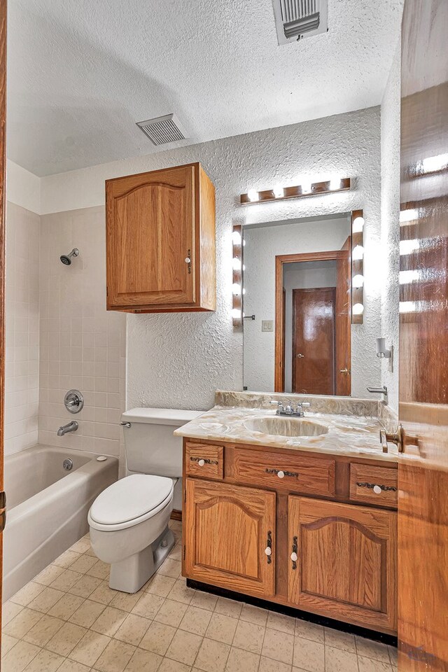 bathroom featuring washtub / shower combination, toilet, a textured wall, and visible vents