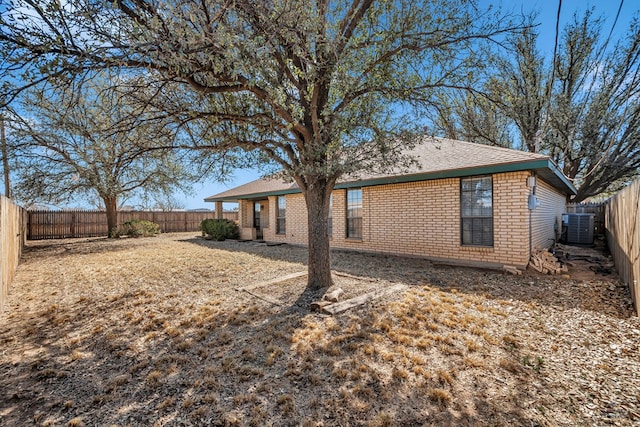 back of house with brick siding, cooling unit, and a fenced backyard