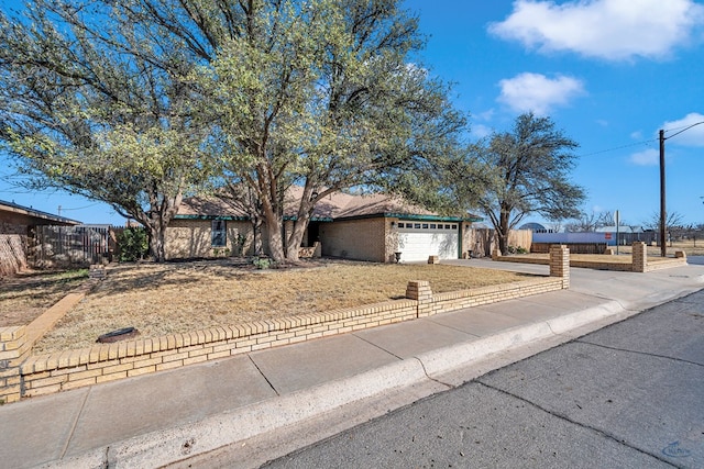 ranch-style house featuring a garage, concrete driveway, and fence