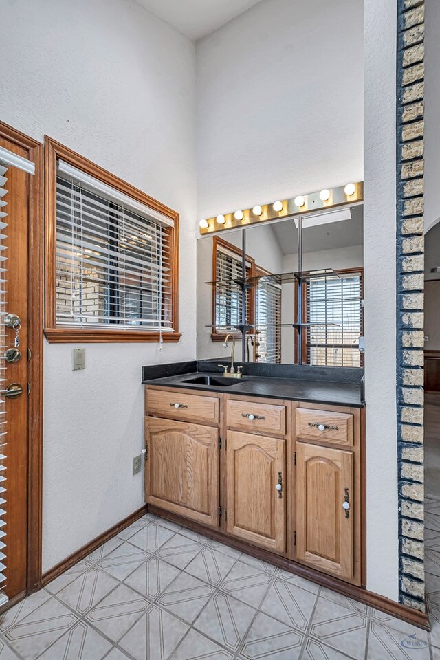 bathroom featuring vanity, a high ceiling, and baseboards